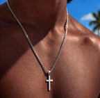Silver tone cross pendant necklace worn against the chest