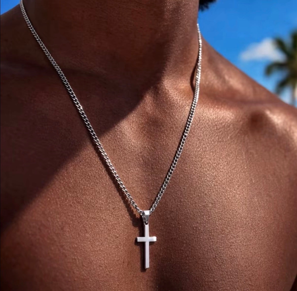 Silver tone cross pendant necklace worn against the chest