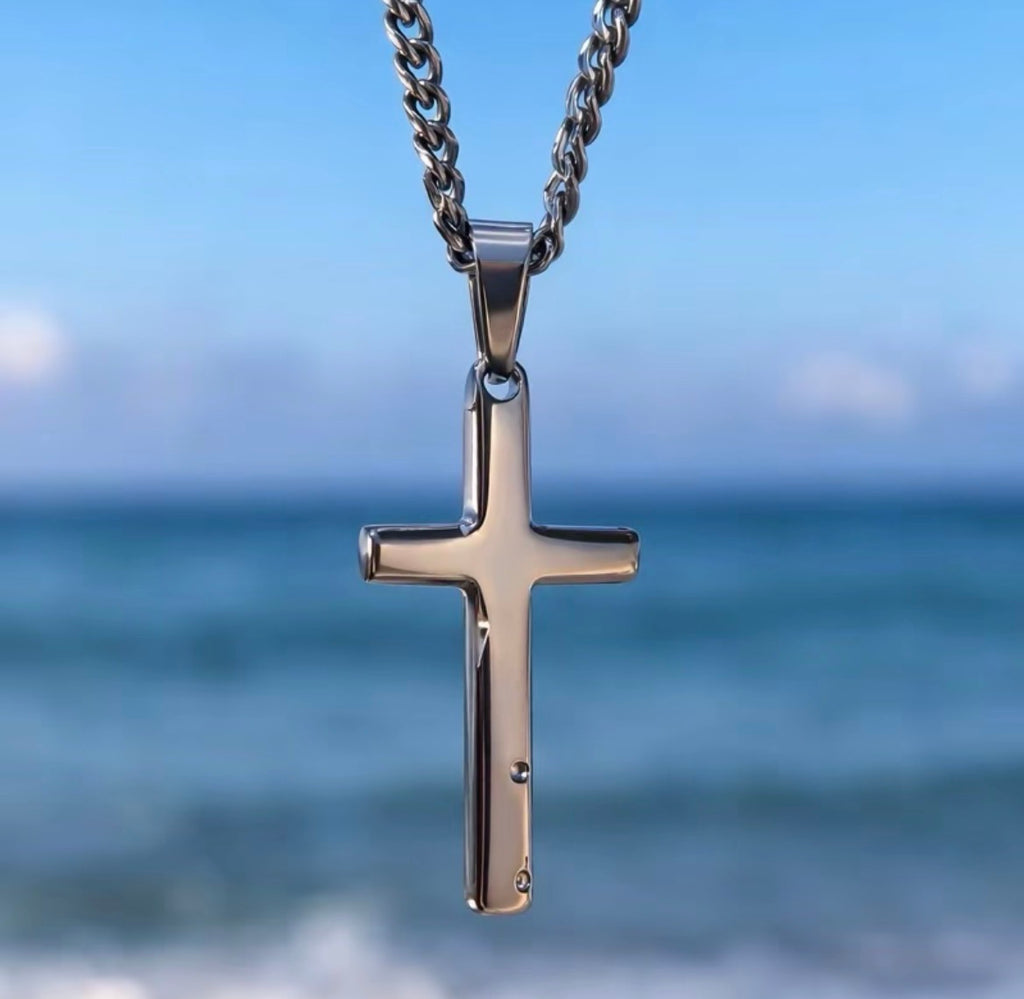 Polished silver tone cross pendant with the sea in the background