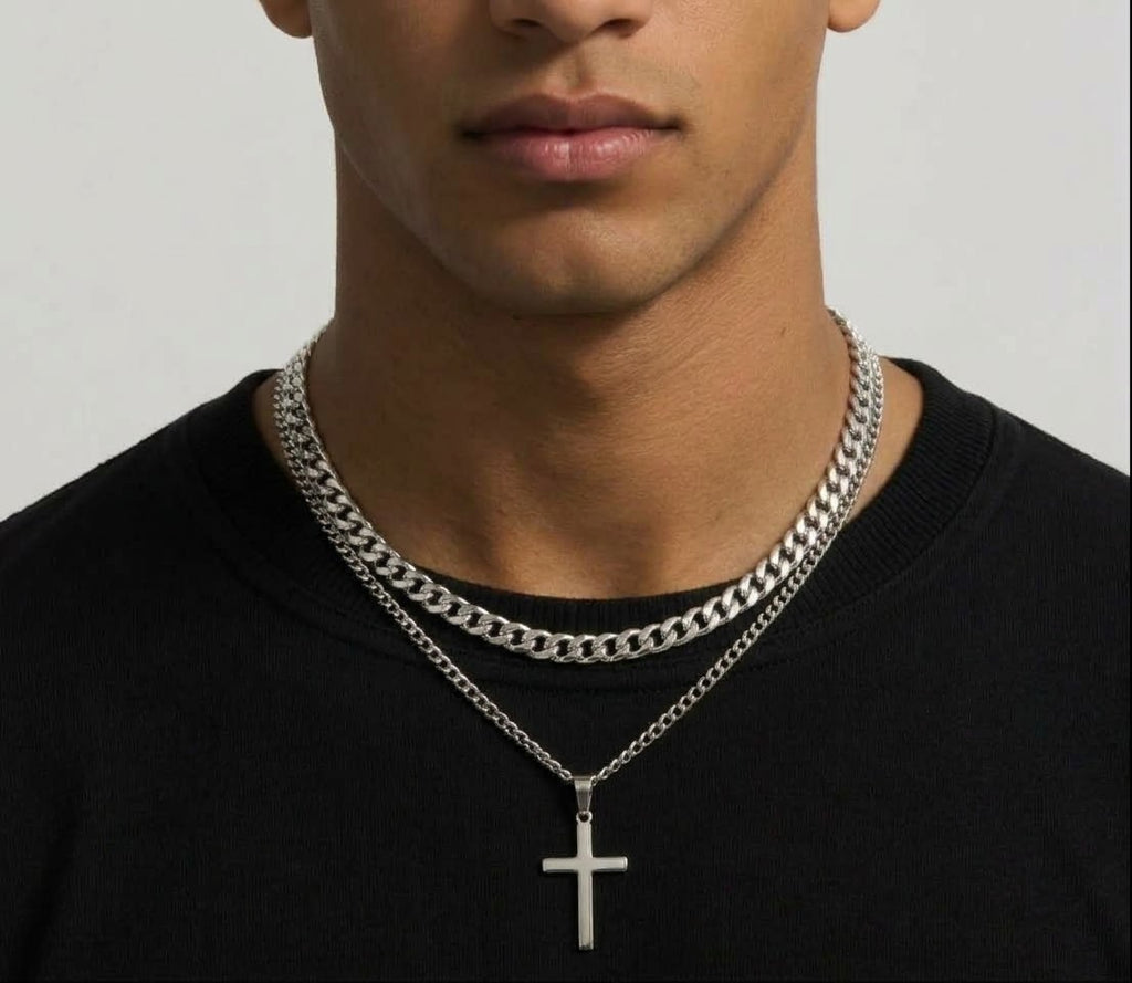 Layered silver tone curb chain and cross pendant necklace worn together