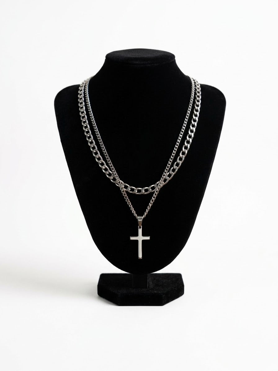 Two silver tone necklaces with a cross pendant on a black bust