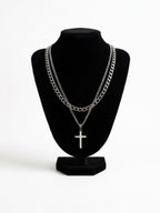 Two silver tone necklaces with a cross pendant on a black bust