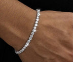 Silver tone tennis bracelet with clear stones worn on a wrist
