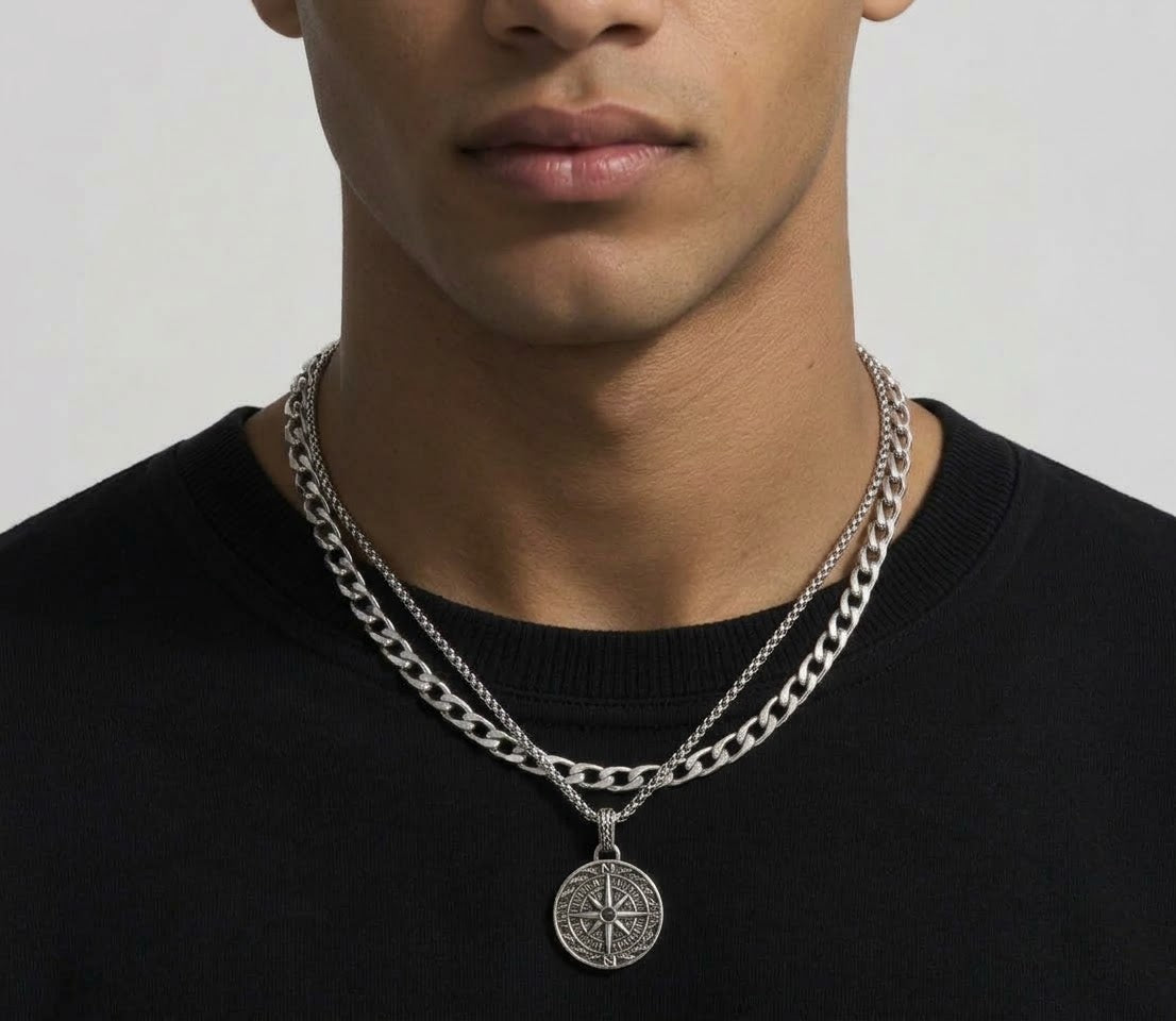 Layered silver tone compass pendant and curb chain necklaces worn together