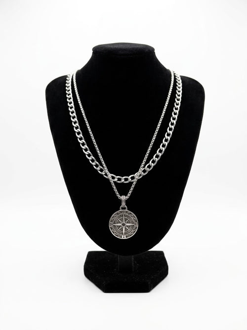 Layered silver tone compass necklace set on a black jewellery bust