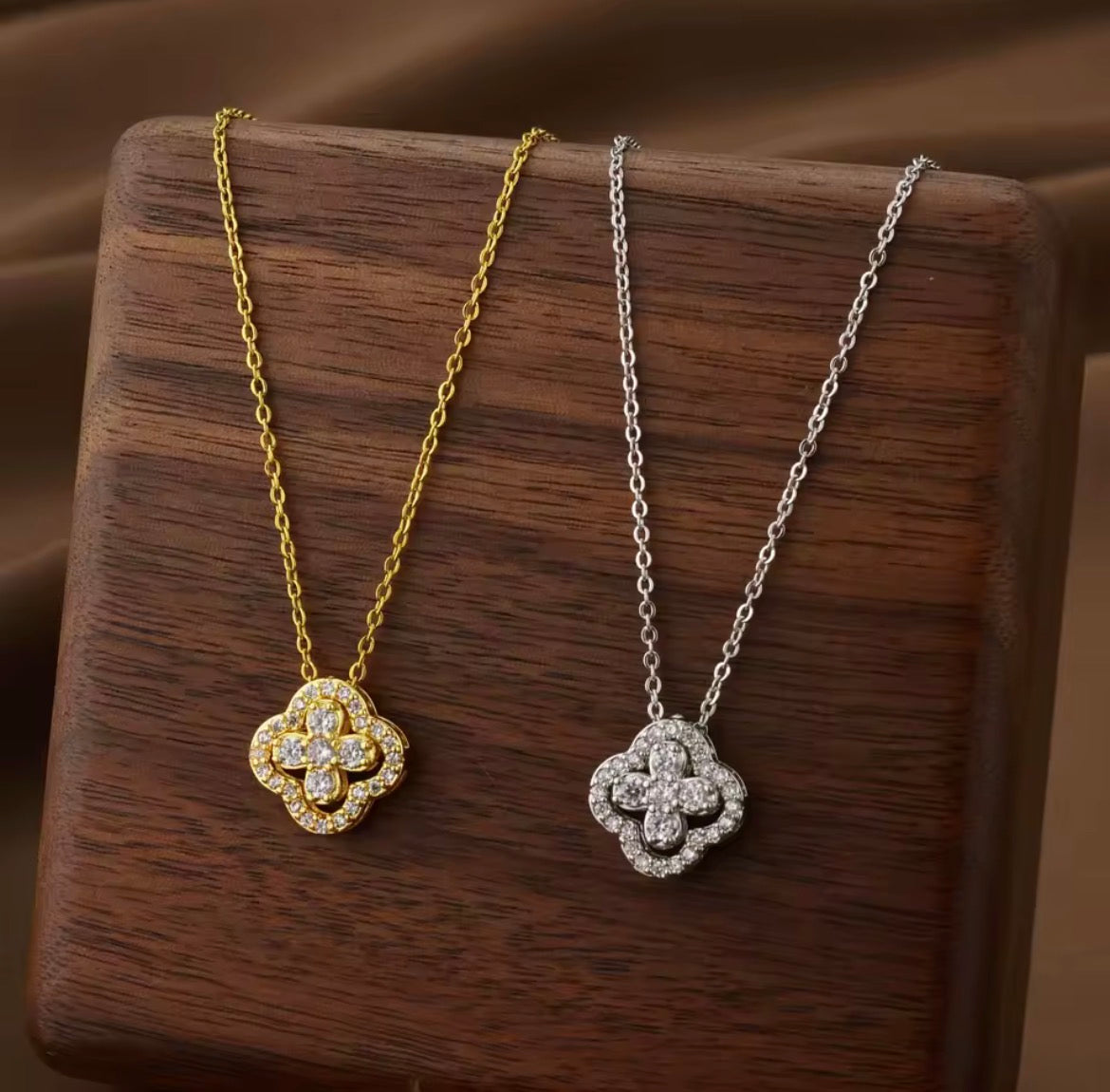 Gold tone and silver tone sparkling clover necklaces displayed side by side