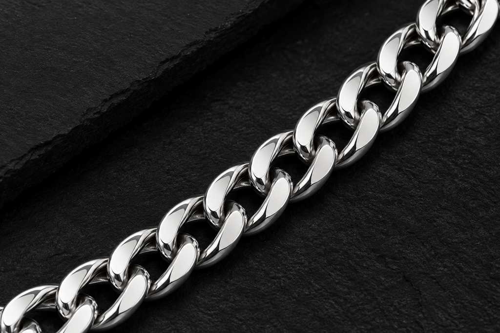 Close-up of polished silver tone curb links on a dark background