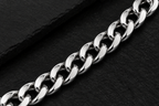 Close-up of polished silver tone curb links on a dark background
