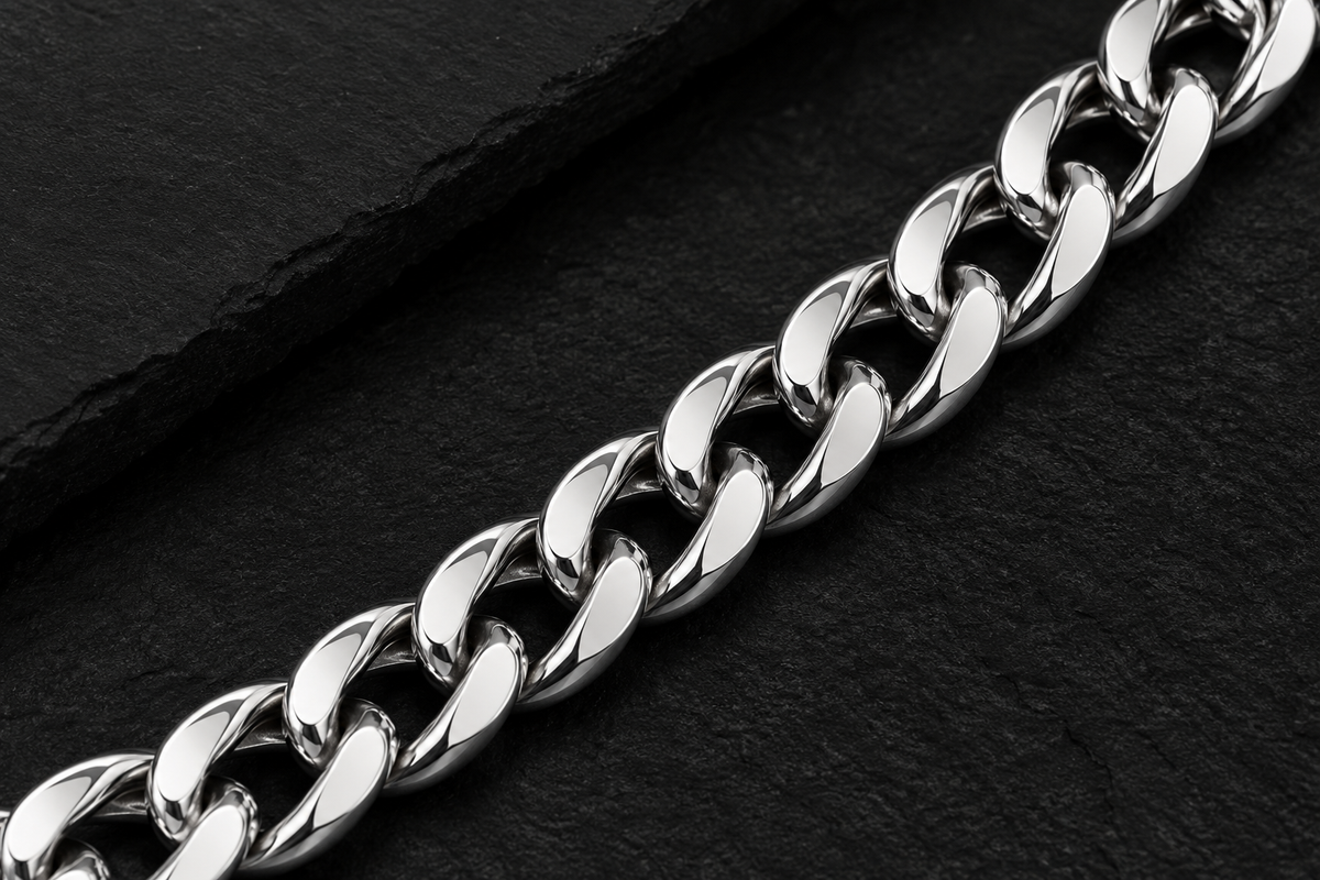 Close-up of polished silver tone curb links on a dark background