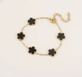 Gold tone bracelet with five black clover charms and an extender chain