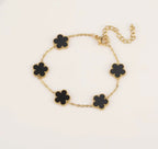 Gold tone bracelet with five black clover charms and an extender chain