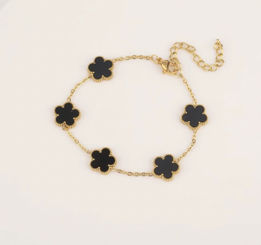 Gold tone bracelet with five black clover charms and an extender chain