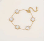 Gold tone bracelet with five white clover charms and an extender chain