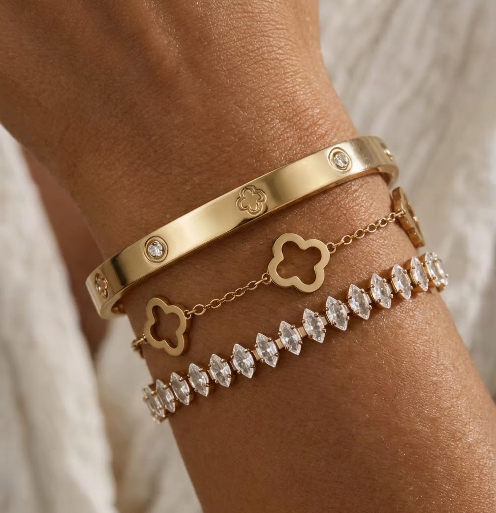 Gold tone flower bracelet, stone-detail bangle and tennis bracelet worn together