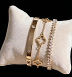 Gold tone flower bracelet, stone-detail bangle and tennis bracelet on a cushion