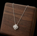 Silver tone sparkling clover pendant necklace displayed on wood