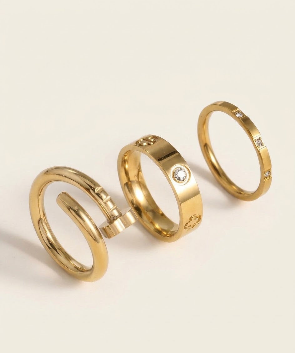 Three gold tone rings with nail-inspired and stone-detail designs