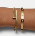 Gold tone nail-inspired and stone-detail bangles worn together